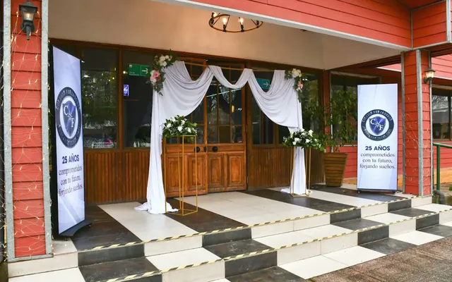 Entrada del colegio decorada con cortinajes blancos y flores para la ceremonia de los 25 años