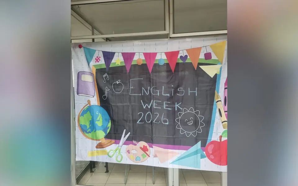 Telón pintado a mano con la leyenda English Week 2026, colgado en un pasillo del colegio